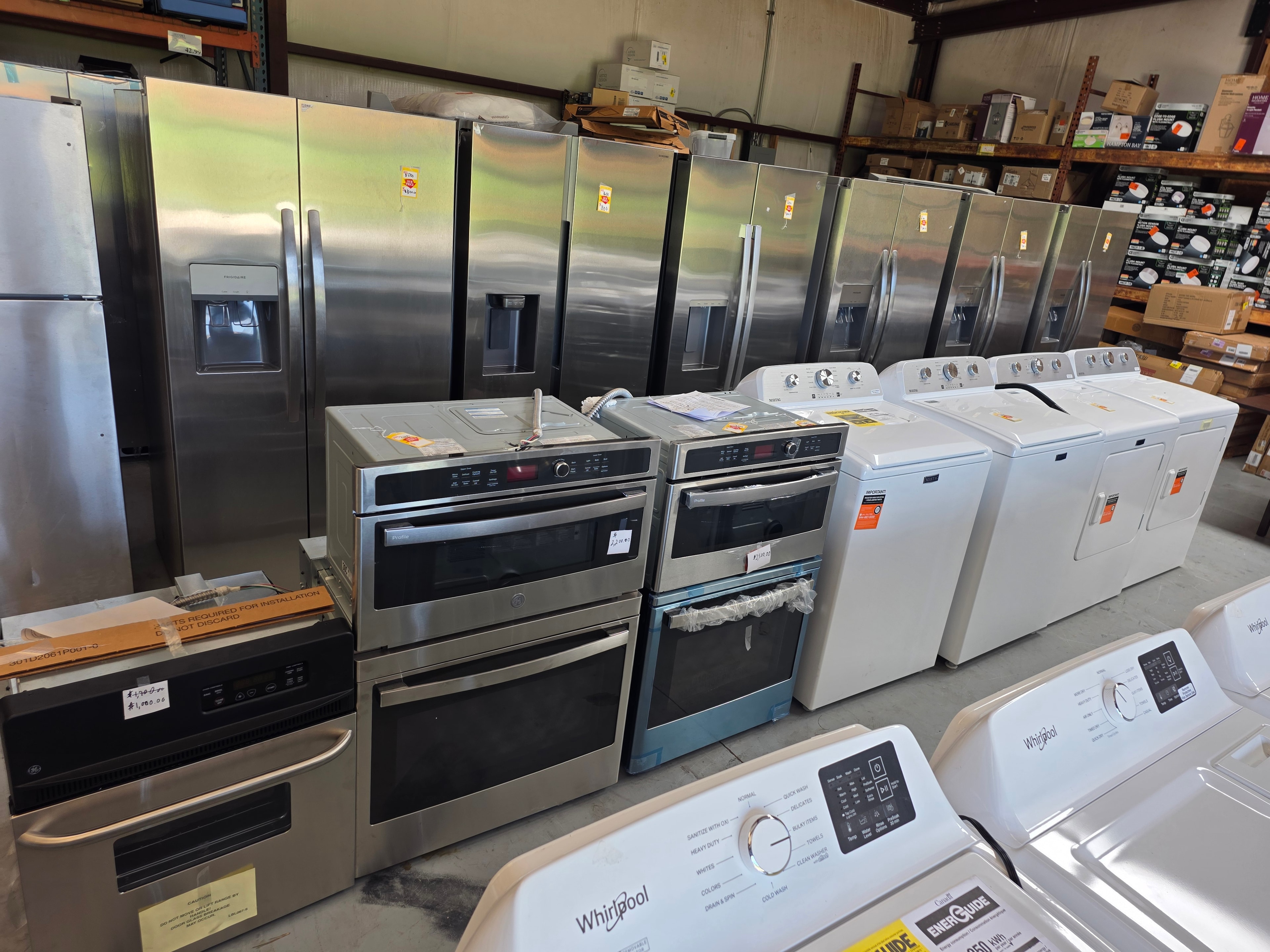 Full warehouse floor view — refrigerators, washers, wall ovens